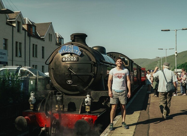 A man standing in front of a steam locomotive with the number 62005. 3