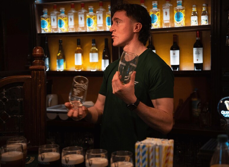 A person holding a glass in a bar with shelves of bottles in the background. 5