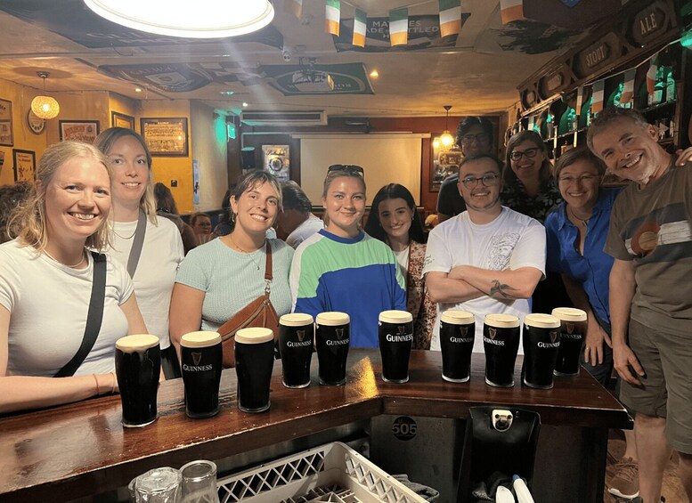 A group of people at a bar with Guinness beer mugs. 3