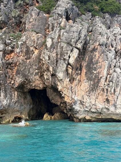 A rocky cave entrance with clear turquoise water. 2