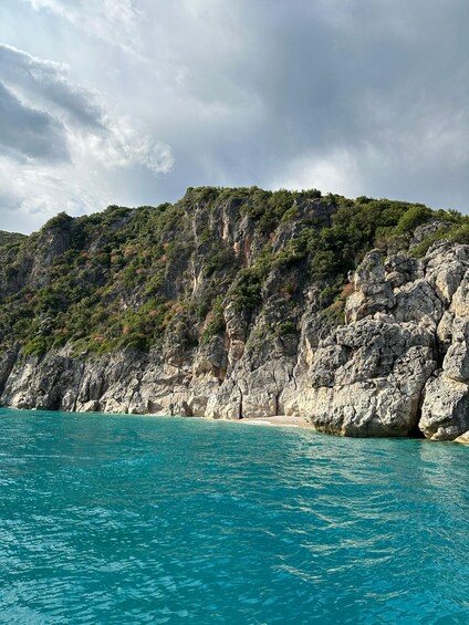 A coastal landscape with clear turquoise waters, rocky cliffs, and a beach. 3