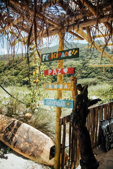 A wooden signpost with multiple directional signs, a surfboard, and a statue of a person in the foreground. 3