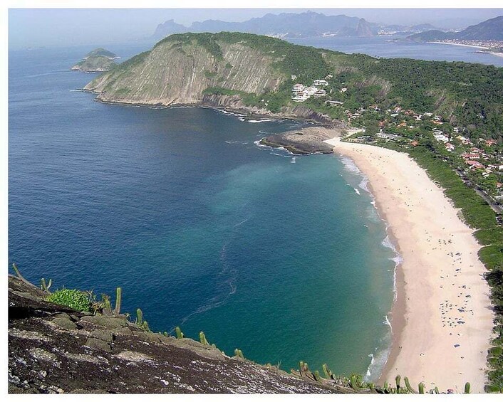 A coastal landscape with a beach, cliffs, and a small settlement. 1