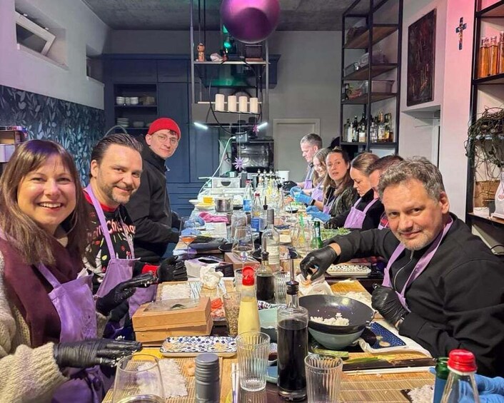 A group of people engaged in a cooking activity around a table with various ingredients and cooking utensils. 1