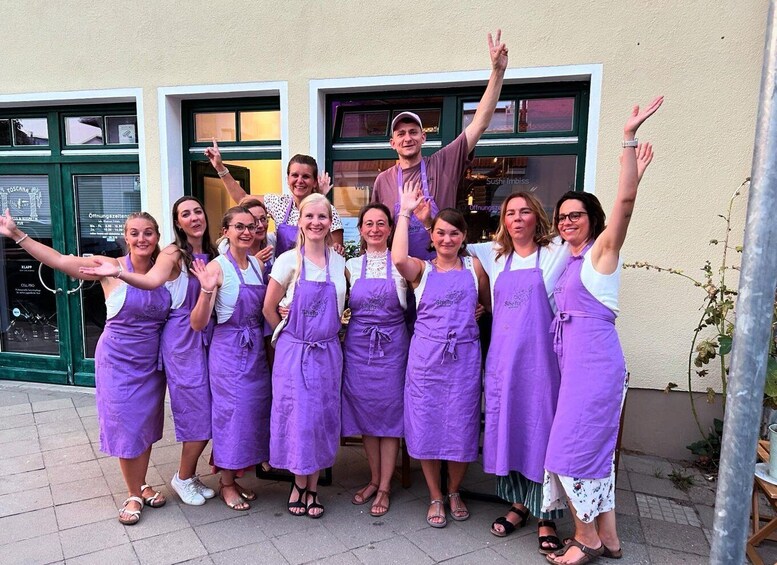 A group of people in purple aprons standing in front of a building with green doors. 3
