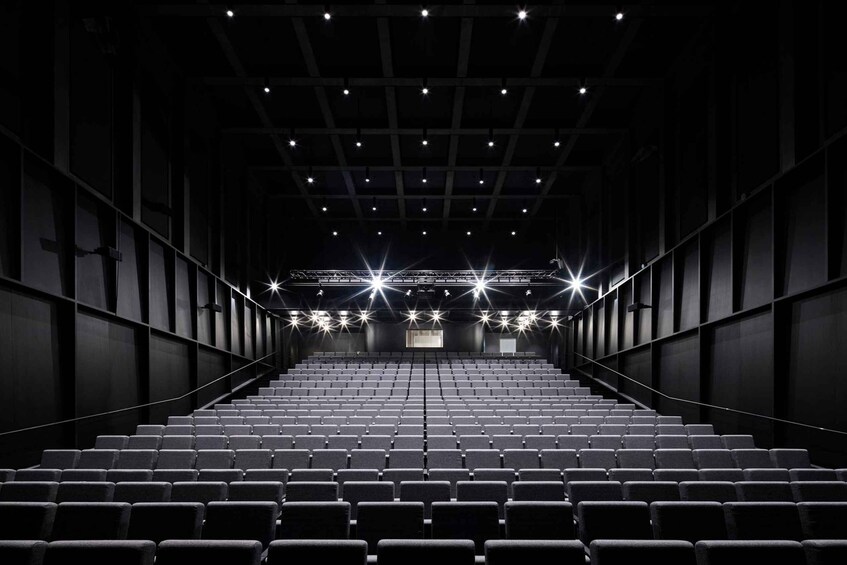 An empty auditorium with rows of seats and a stage at the front. 3