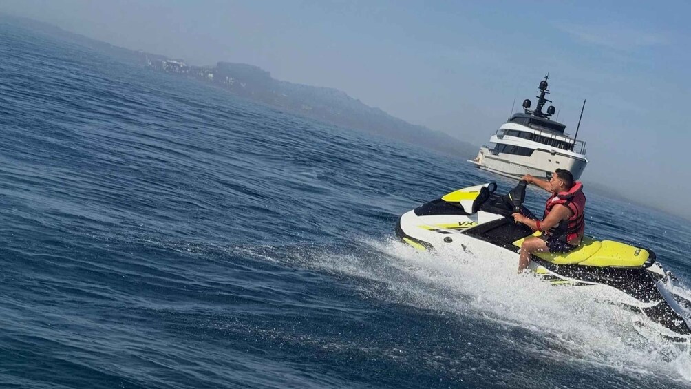 A person riding a jet ski on the water with a mountainous coastline in the background. 2