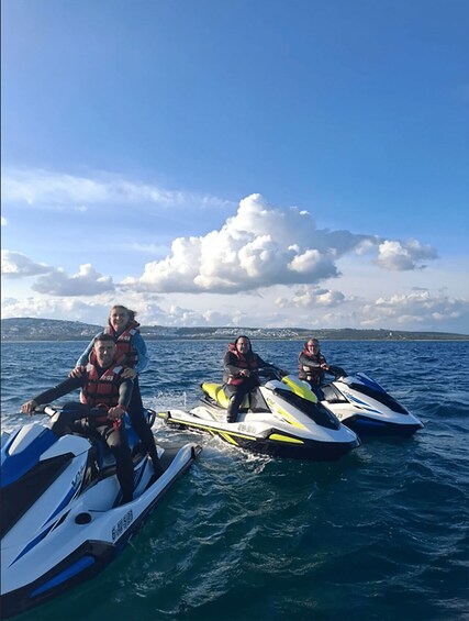 Three people on jet skis in the ocean with a clear sky. 3