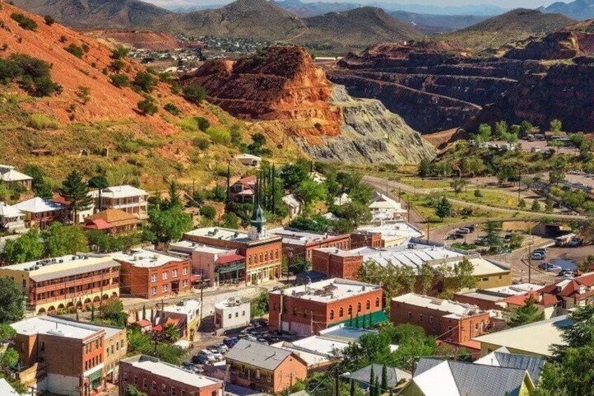 A town with red brick buildings, a prominent church, and a valley with mining activity. 2