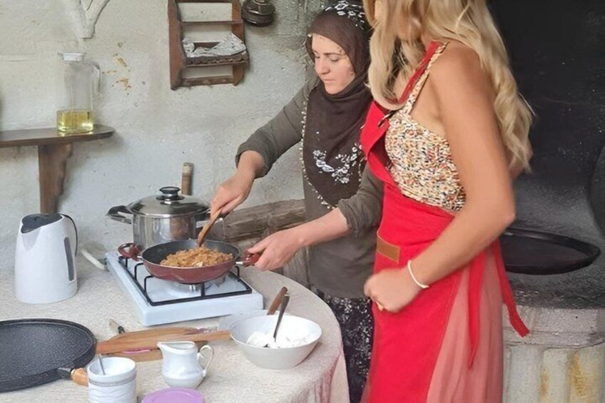 Two people cooking with a stove, pots, and a frying pan. 5