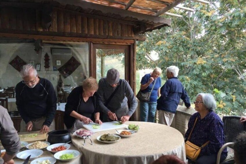 A group of people preparing food outdoors with a table set for a meal. 4