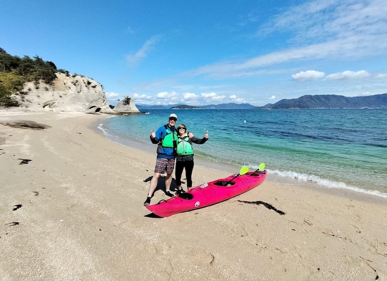 Two people on a beach with a pink kayak. 4