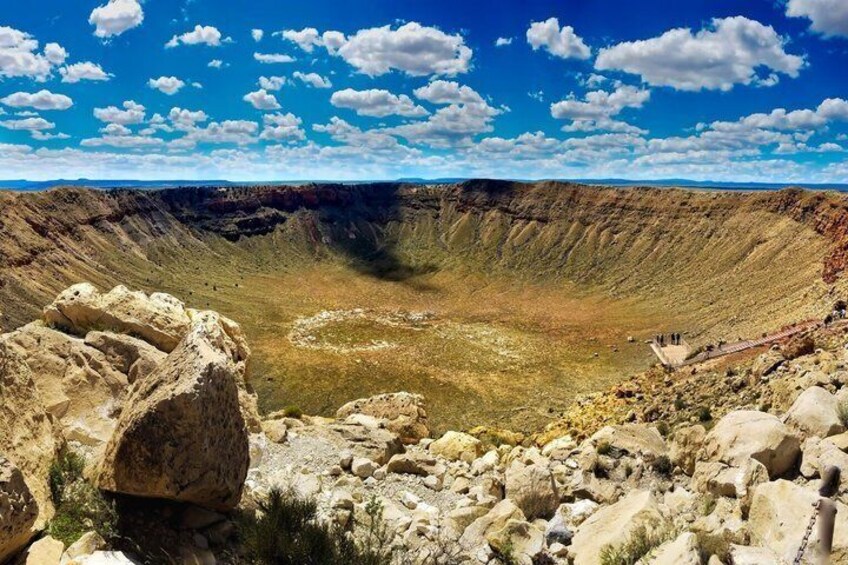 A large crater with a circular pattern in the center, surrounded by rocky terrain and sparse vegetation. 5