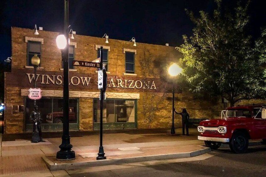 A vintage car parked in front of a building with a sign reading 'WINSLOW ARIZONA.' 3
