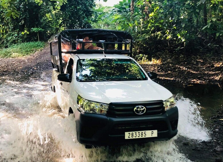 A white Toyota pickup truck driving through a shallow river. 1