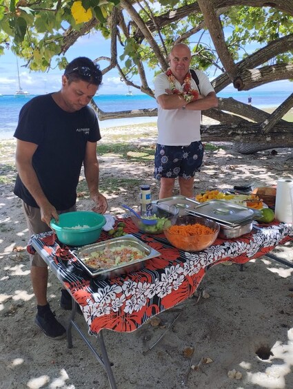 A beachside barbecue with a table laden with food and a person grilling. 3
