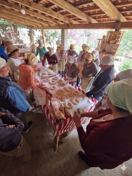A group of people seated around a table with doughnuts, under a wooden structure. 5