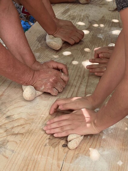 Hands shaping dough on a wooden surface. 1