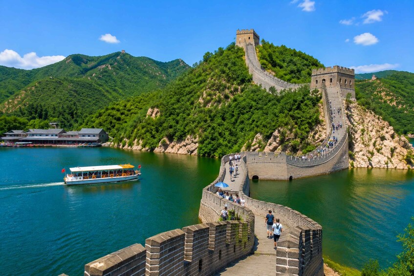 The Great Wall of China winding along a river, with a boat and tourists. 1