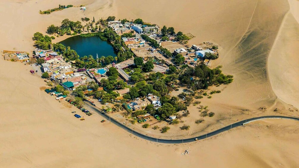 An aerial view of a desert settlement with a central water body, surrounded by buildings and sparse vegetation. 4