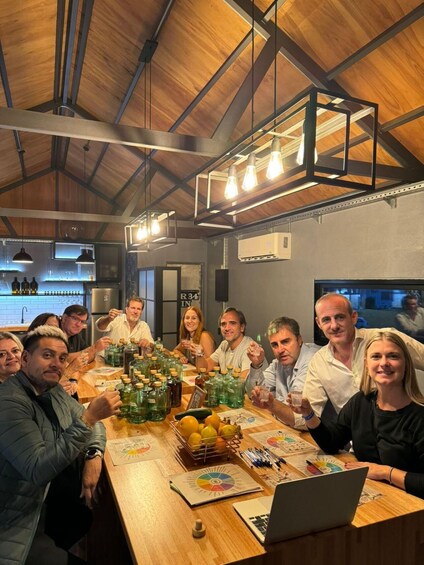 A group of people around a table with drinks and a laptop, in a room with wooden beams and hanging lights. 3
