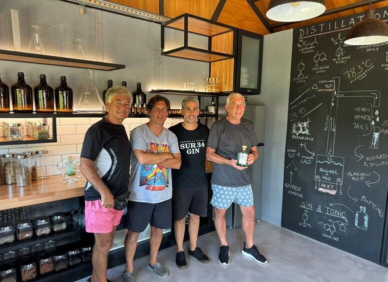 A group of people in a distillery with shelves of bottles and a chalkboard with distillation diagrams. 1