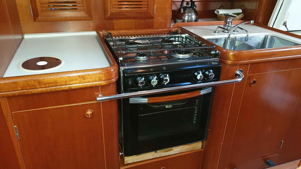 A kitchen with wooden cabinets, a stove, a sink, and a kettle. 3