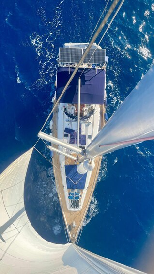 A sailboat with a cabin, deck chairs, and a mast. 1