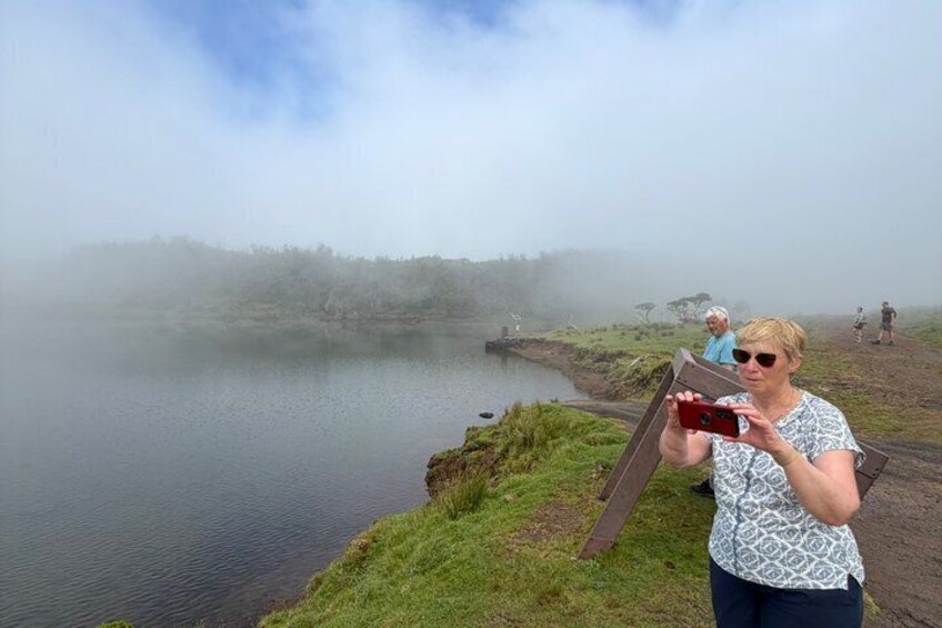 A person taking a photo of a misty lake with a wooden bridge. 2