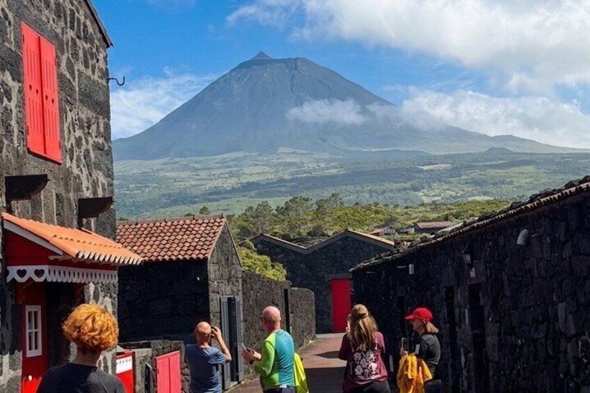 A group of people walking in a village with a mountain in the background. 1
