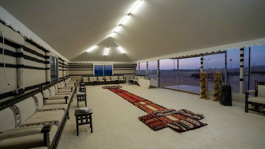 A tented room with sofas, a long red carpet, and a view of a desert landscape. 4