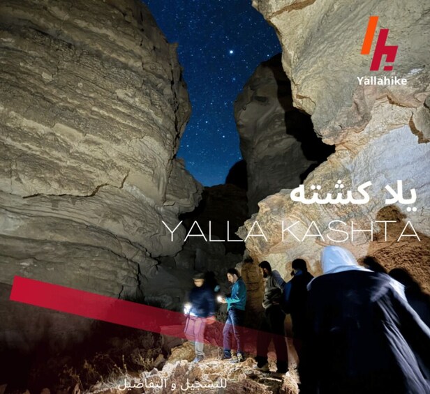 A starry night sky viewed through a cave opening, with people standing inside. 1