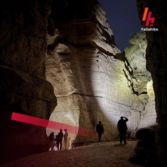 A group of people exploring a rock formation at night. 3