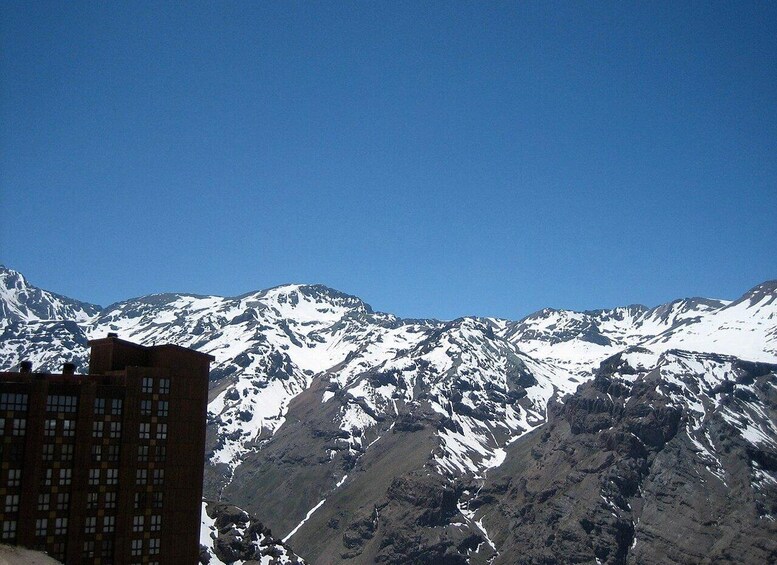 A mountain range with snow-capped peaks and a building in the foreground. 2