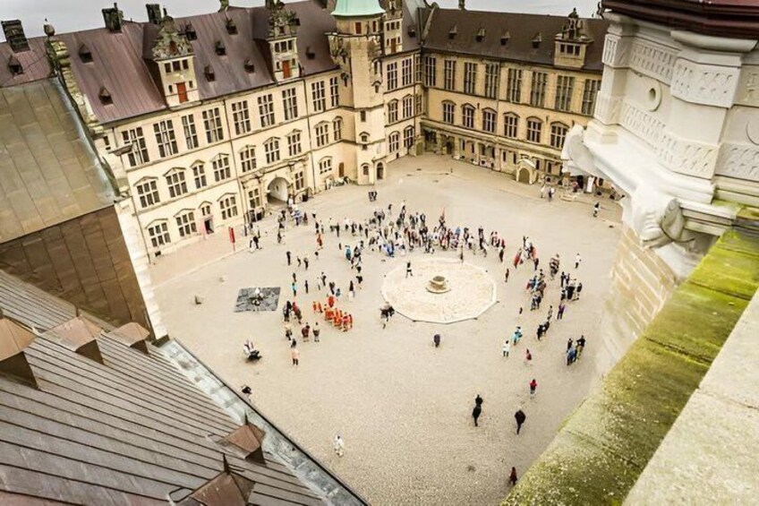 A courtyard with a central fountain, surrounded by historic buildings with multiple windows and a large, ornate entrance. 2