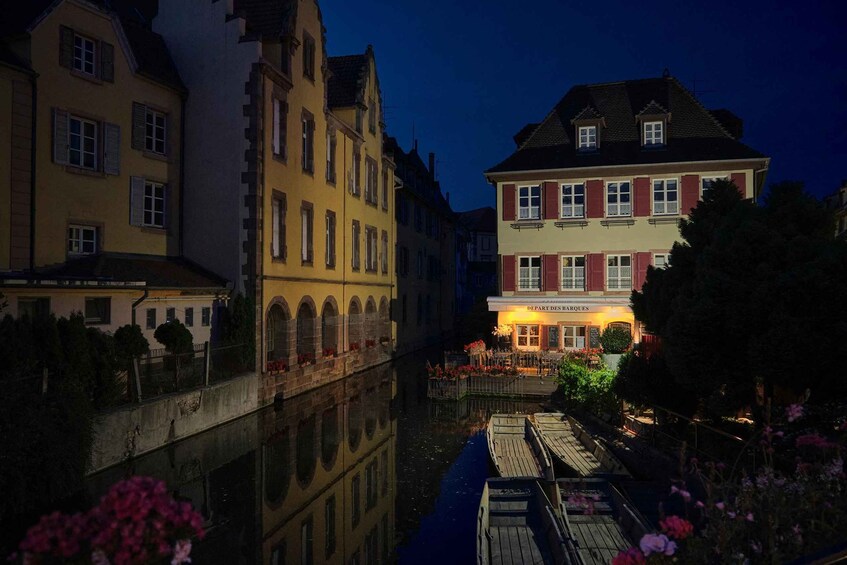 A canal with buildings on either side, a wooden dock, and a restaurant named 'DEPARTIES DES MARQUES' with outdoor seating. 5