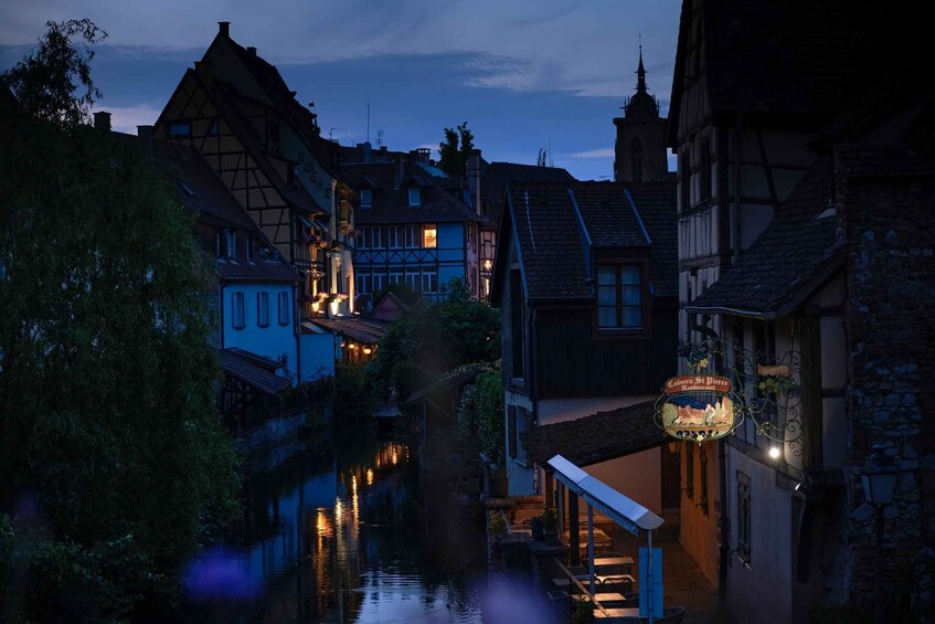 A riverside town at dusk with illuminated buildings and a church spire. 3