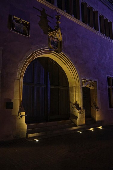 A historic building with a large arched entrance, ornate decorations, and a statue above the door. 4