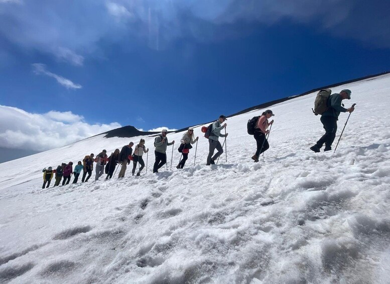 A group of hikers ascending a snow-covered slope under a clear blue sky. 5