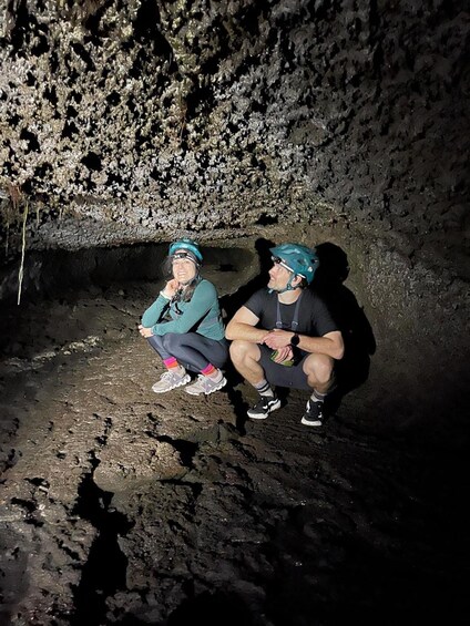 Two people sitting in a cave with rough, rocky walls. 3