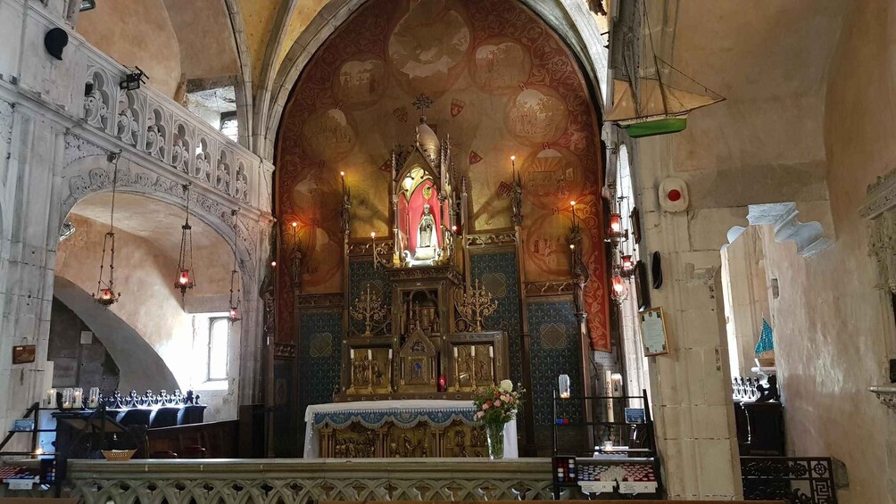 An ornate church interior with a central altar, stained glass windows, and a vaulted ceiling. 3