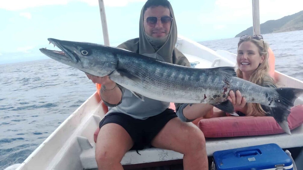 A person holding a large fish on a boat. 4