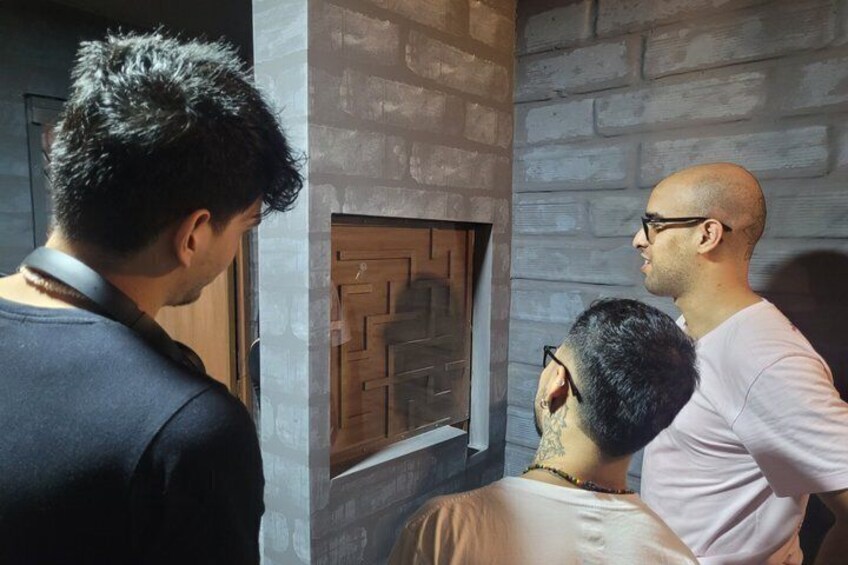 Three people looking at a fireplace with a geometric pattern. 5
