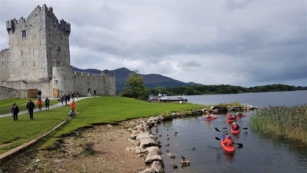 A castle, a lake, kayakers, and a grassy path. 3
