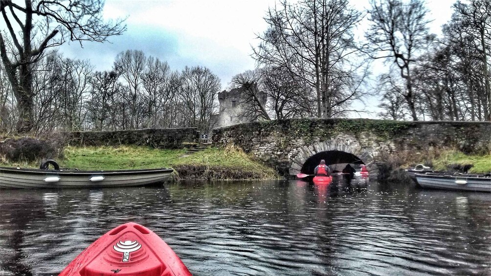 A calm river with boats, a stone bridge, and a castle in the background. 2