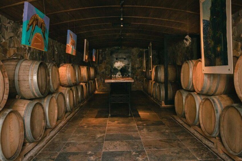 A cellar with wooden barrels and artwork on the walls. 4