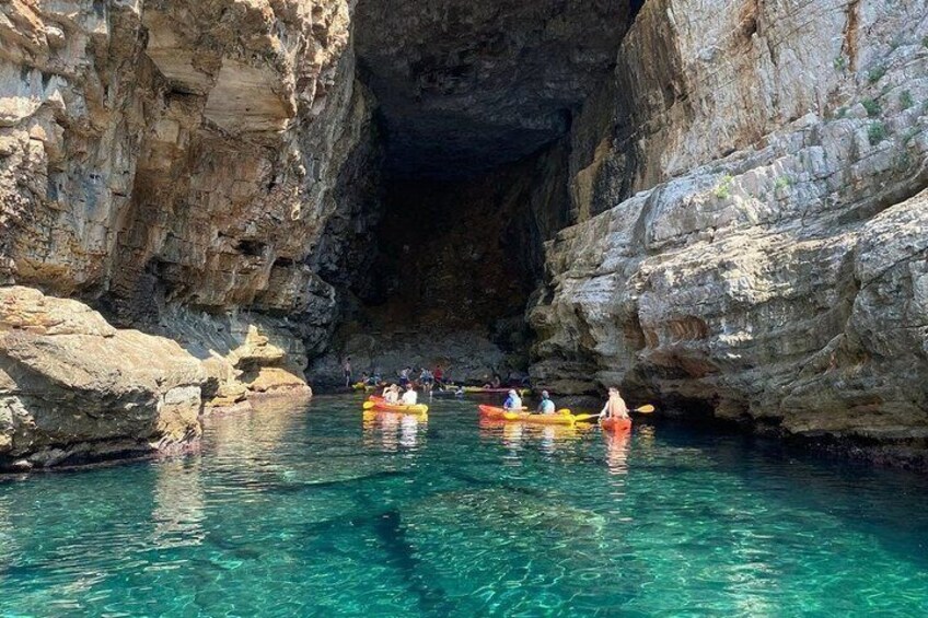 Kayakers in a clear blue waterway between rocky cliffs. 2