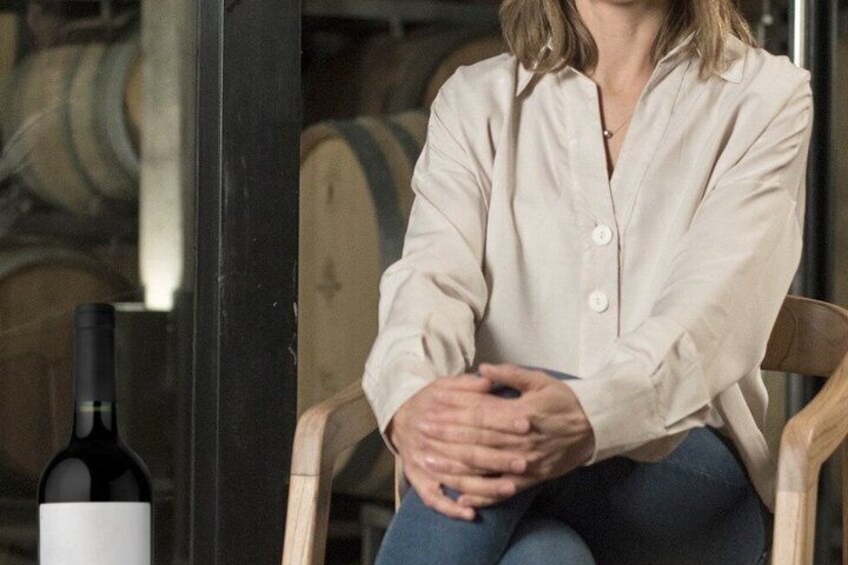 A person sitting on a chair with a bottle of wine on the table. 5