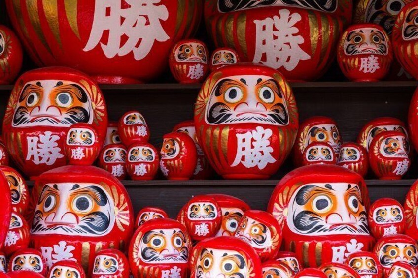 A collection of red and gold Japanese dolls with painted faces. 1