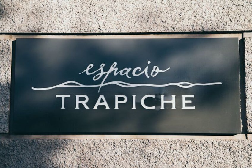 A sign with the text 'esfacio TRAPICHE' on a textured wall. 1